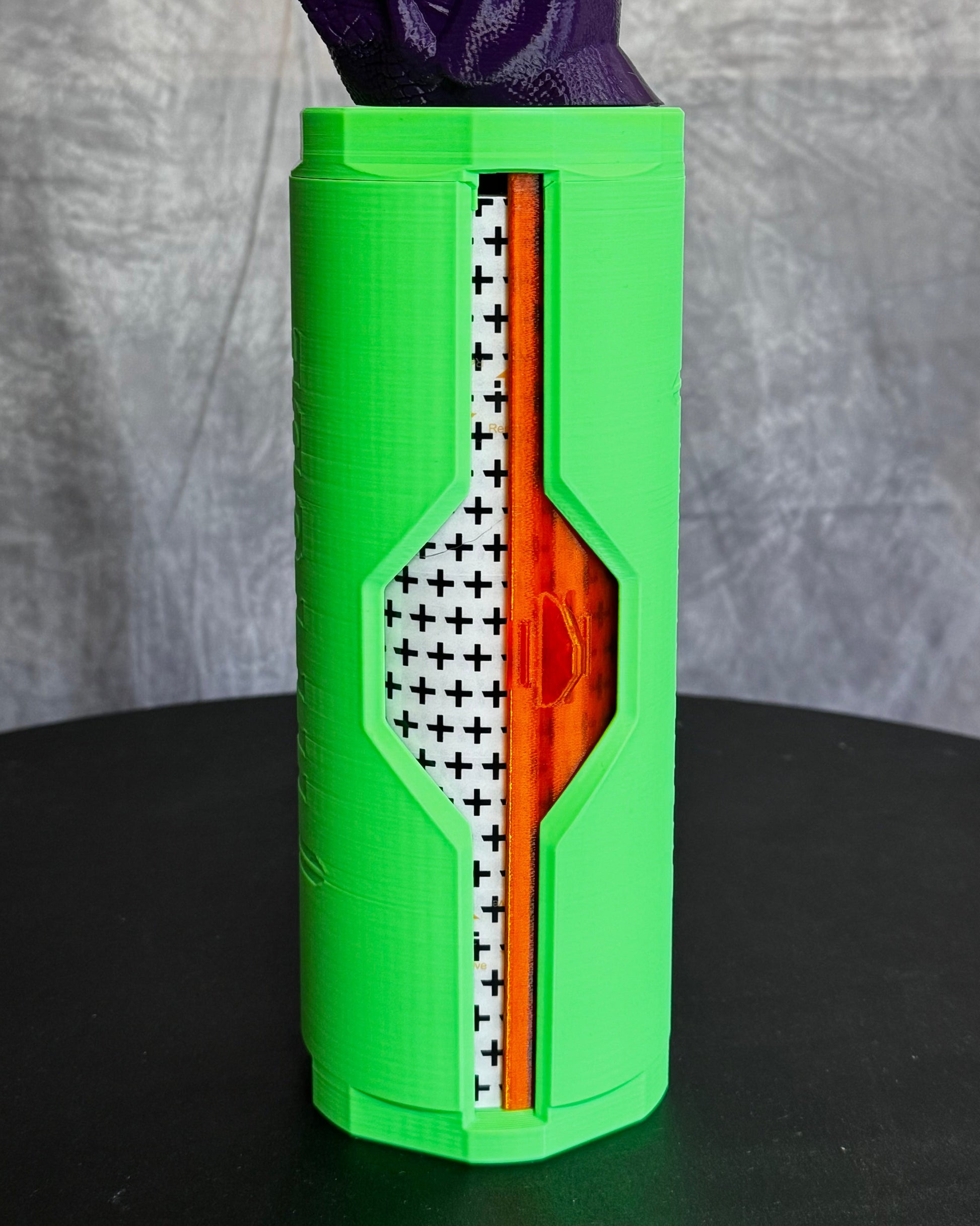 Green cylinder with tattoo bandage rool inside on black table.