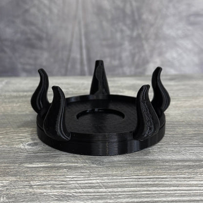 Black plastic base with five tentacles, sitting gray wood table.